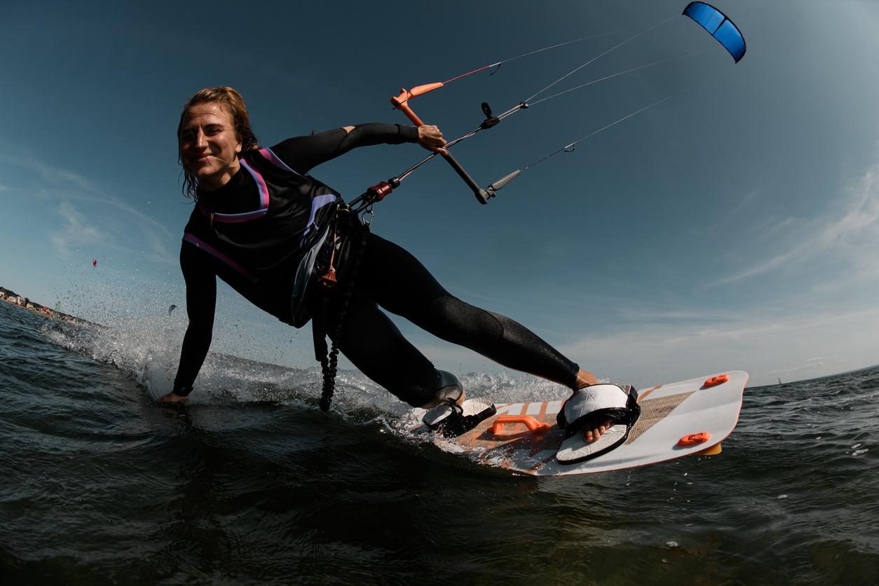 Smiling girl rides on the waves in a black tight-fitting wetsuit