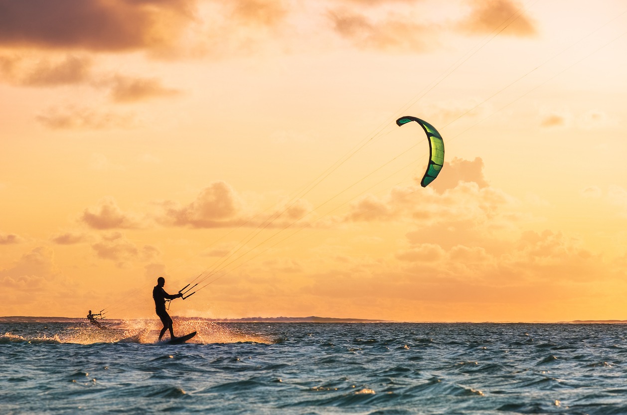 Sunset sky over the Indian Ocean bay with a two kiteboarders riding kiteboards