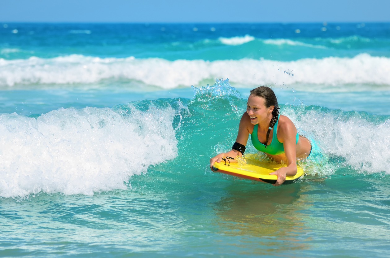 Young attractive woman bodyboards on surfboard with nice smile