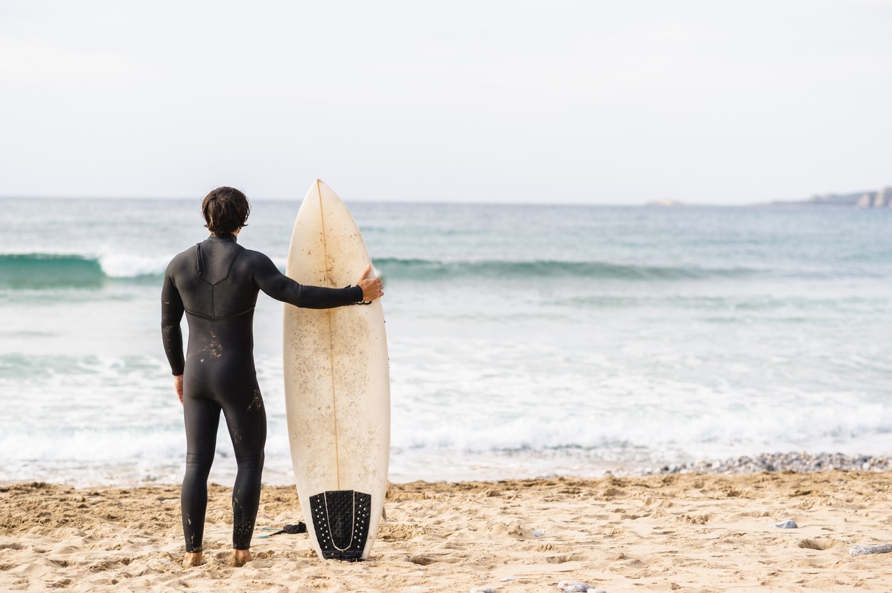 surfer man wearing diving suit leaning on the surfboard