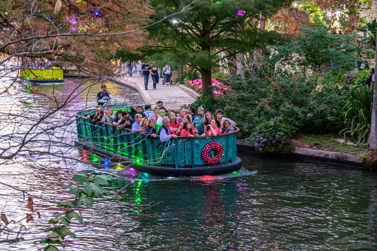 A crowded decorative boat gliding along the San Antonio River Walk