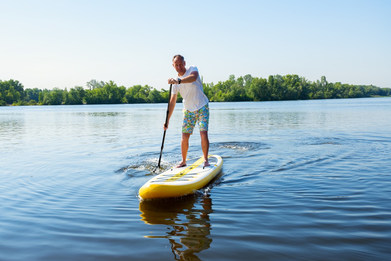 Joyful man sails on a SUP board in large river