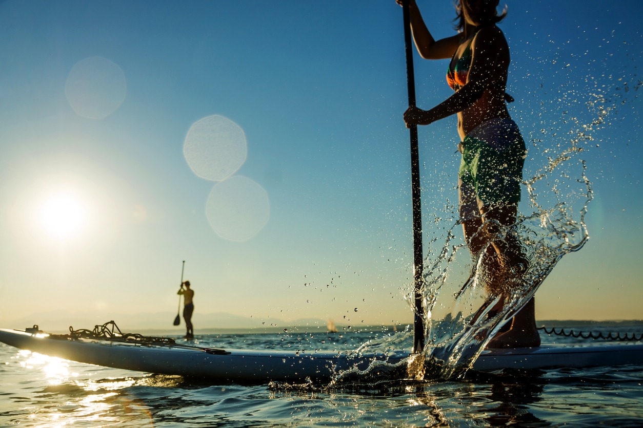 Woman paddling stand up paddle board splashing water