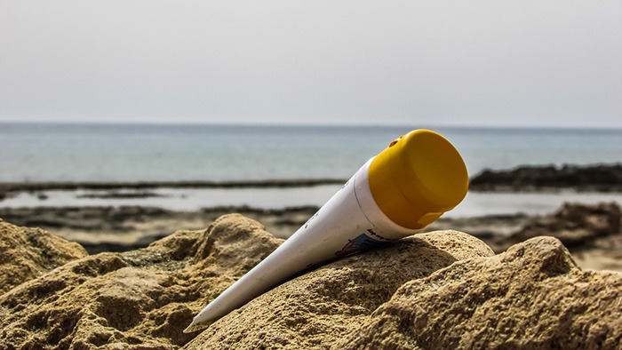 sunscreen tube lying on the rocks in front of the beach