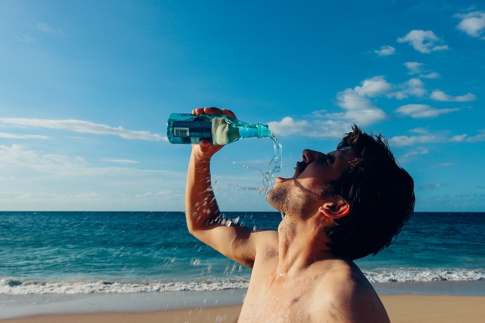 man drinking water by the beach