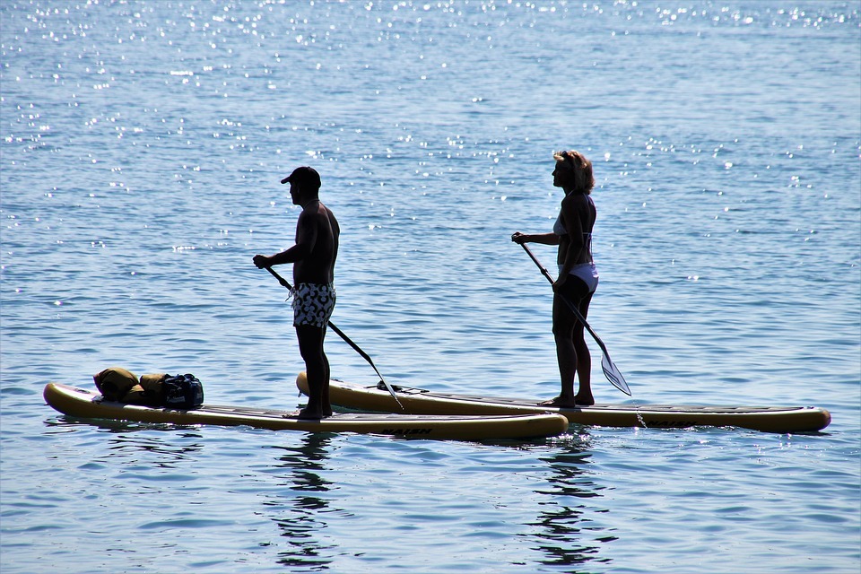 man and woman stand up paddleboarding