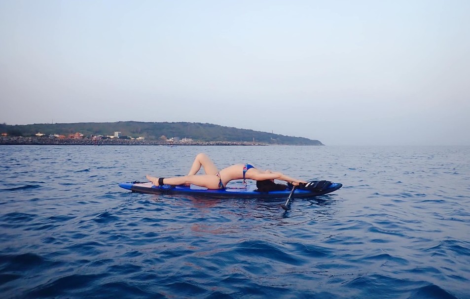 A woman wearing blue swimwear, performing yoga, relaxing at the ocean