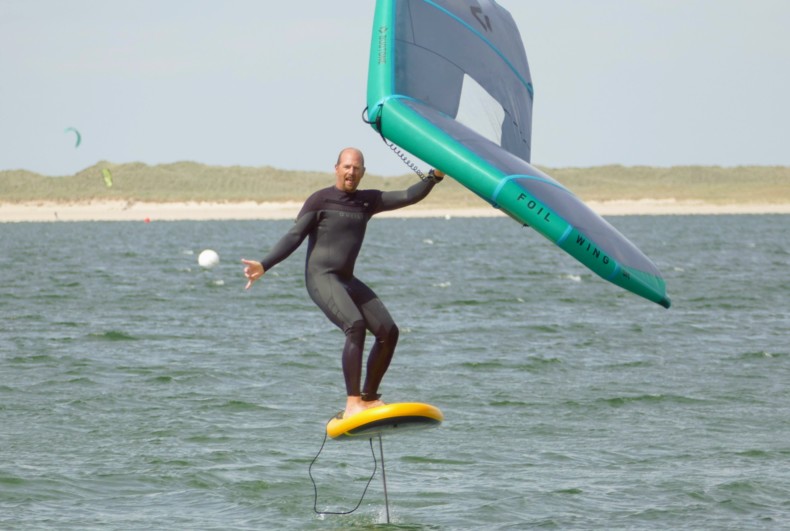 A man wing foiling with a wing and an inflatable board mounted on a hydrofoil