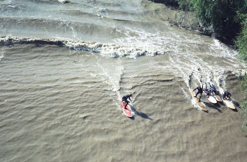 A group of surfers surfing the Severn Bore