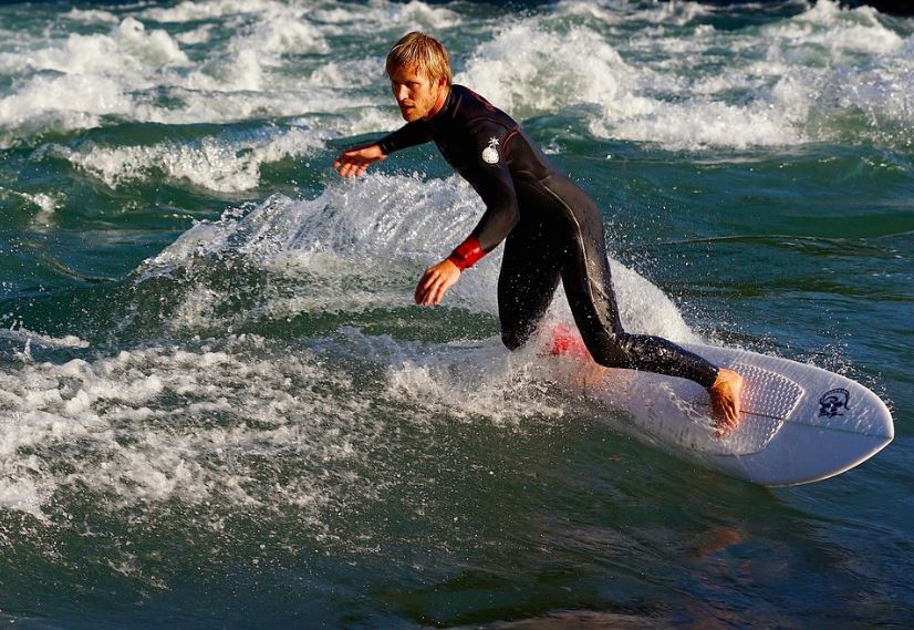 A man wearing a wetsuit while river surfing