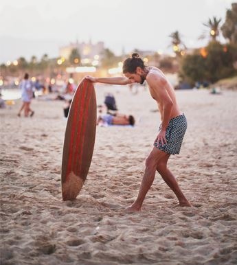 A skimboarder stretching his hamstrings before a ride