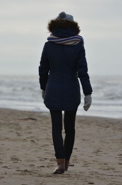 A woman wearing winter clothes on the beach