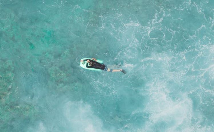 an aerial view of a person riding a bodyboard in the ocean