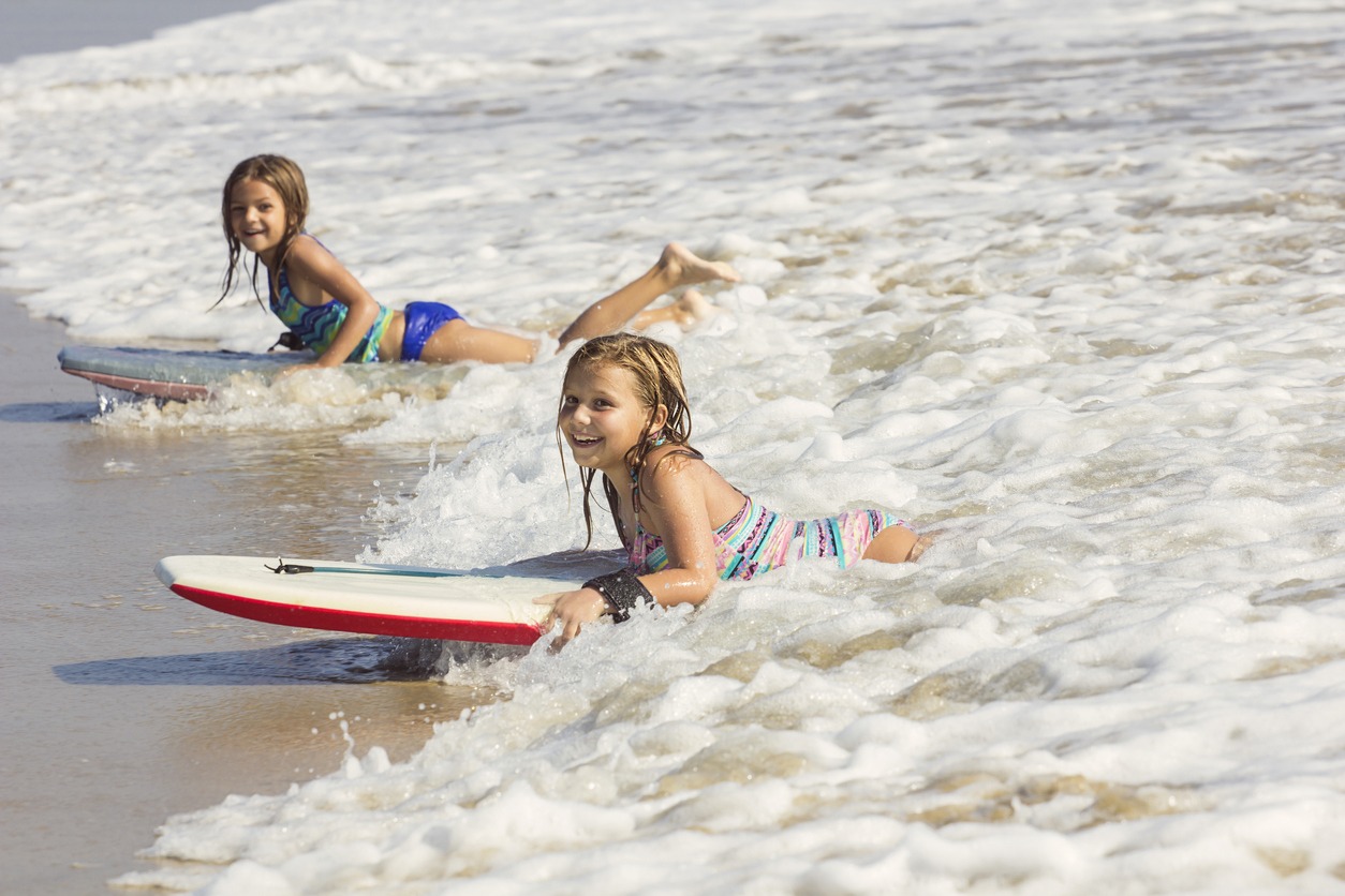 little girls boogie boarding in the ocean waves