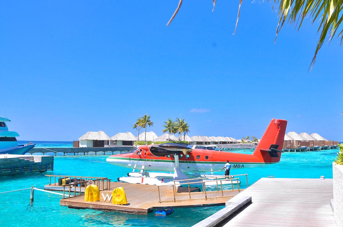red and white seaplane parked beside a beach boardwalk